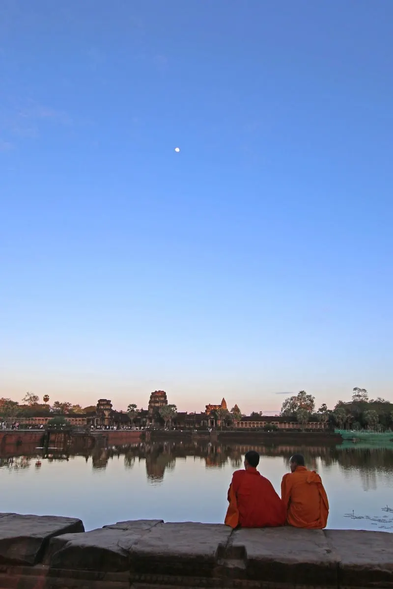 Two monks sitting by the moat watching the moon rise over Angkor Wat.