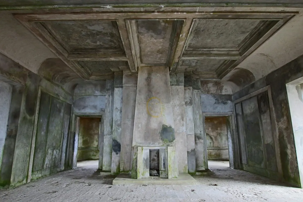 Empty, mildewed salon with a fireplace inside the abandoned Bokor Palace Hotel.
