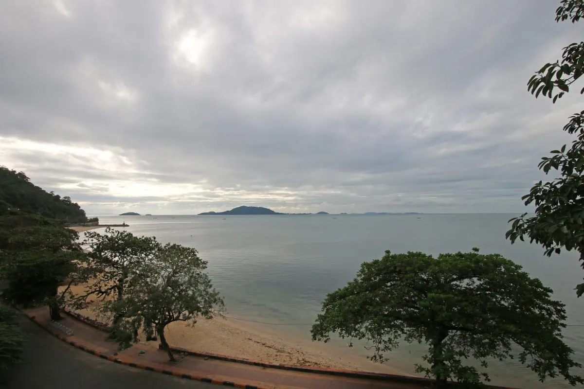 Kep beach and calm sea with distant islands under heavy clouds.