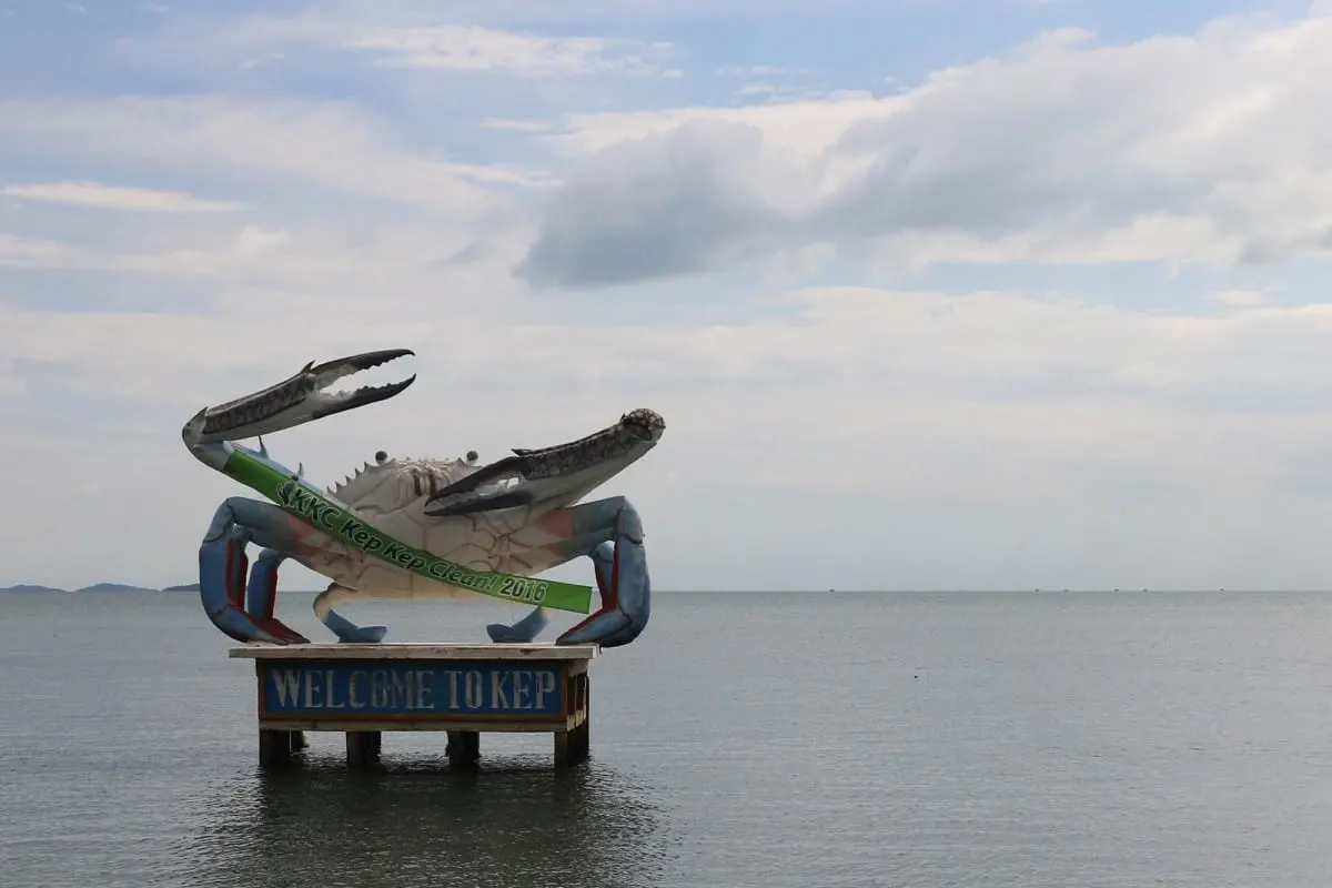Giant crab statue above a Welcome to Kep sign standing in the sea.