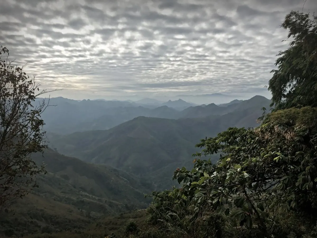 Forested mountain ridges under a dappled cloudy sky in northern Laos