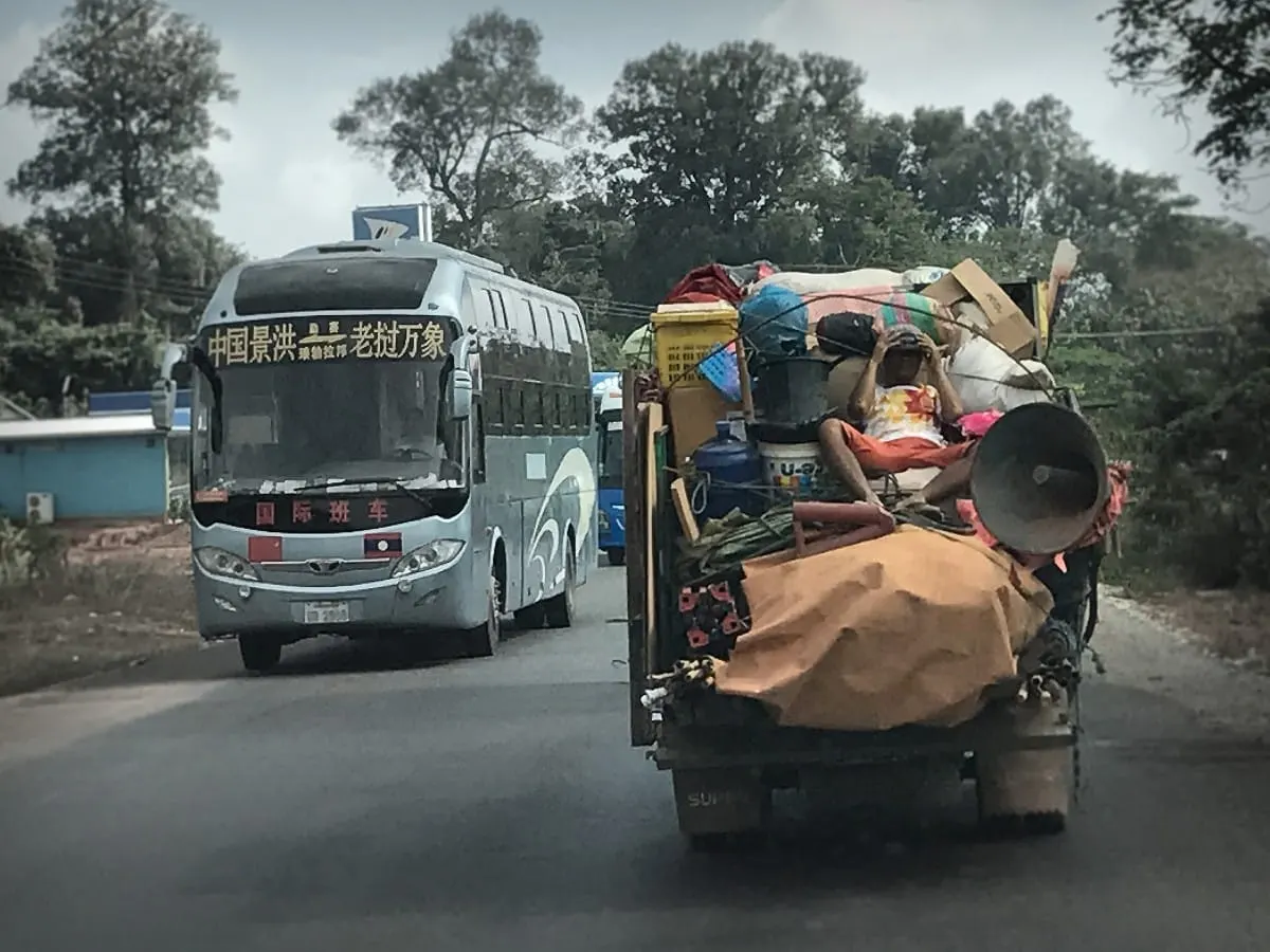 Overloaded truck and international bus on a road in Laos