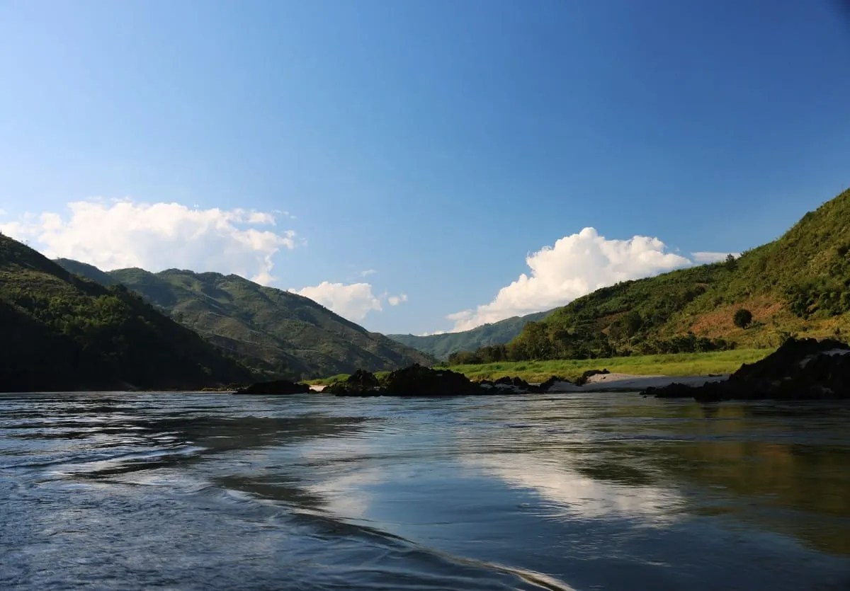 Calm Mekong River between green hills under blue sky in northern Laos