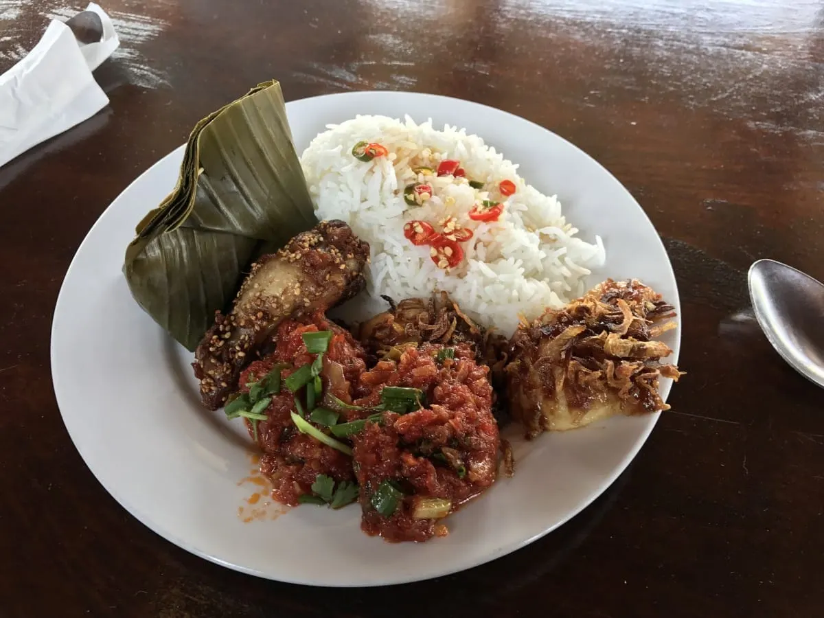 Lao lunch plate of rice, chicken, tomato relish and banana-leaf parcel