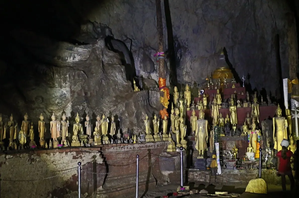 Hundreds of golden Buddha figures lining the dim upper cave at Pak Ou