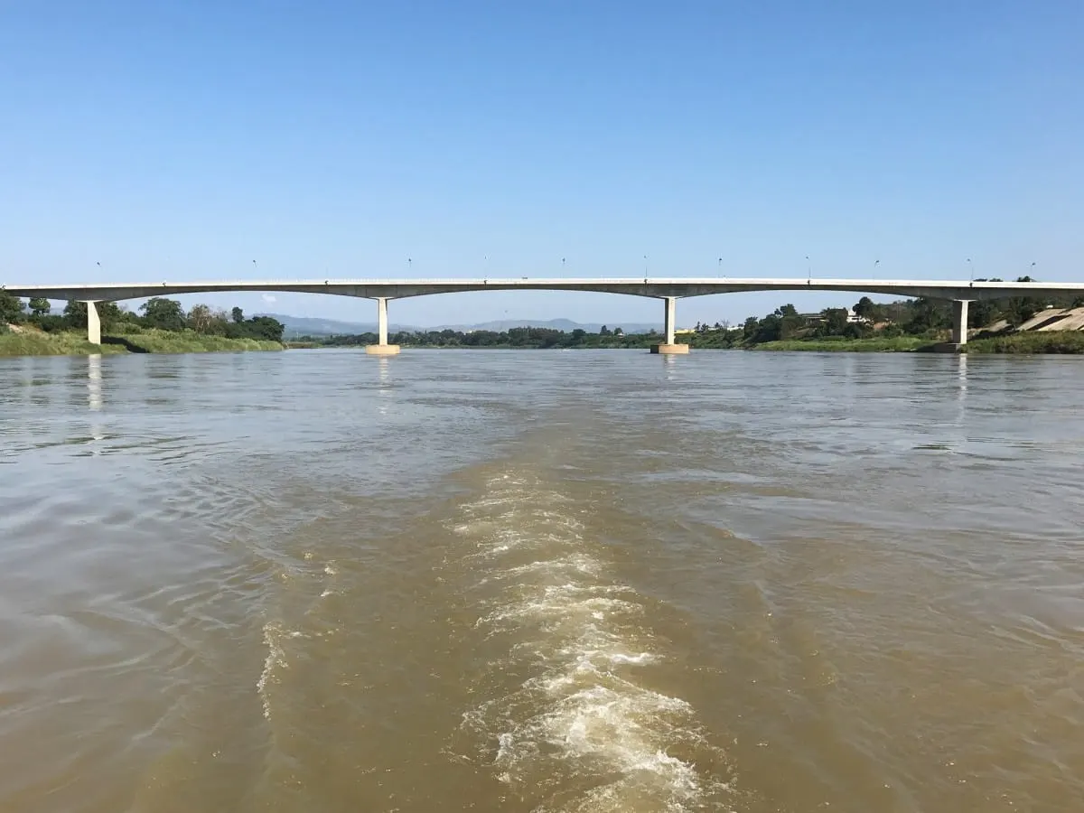 Thai-Lao Friendship Bridge spanning the brown Mekong, seen from a boat's wake
