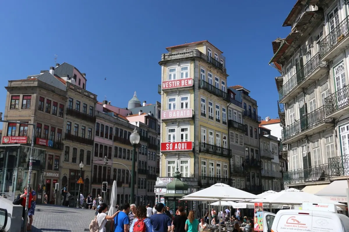 Crowded square in downtown Porto lined with tall tiled buildings and balconies