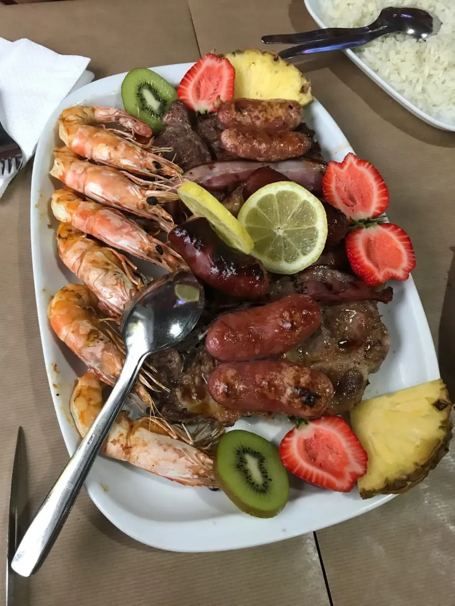 Platter of grilled prawns, sausages and meats garnished with fruit