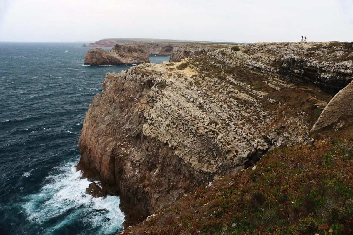 Rugged limestone cliffs above churning sea on a windswept day near Sagres