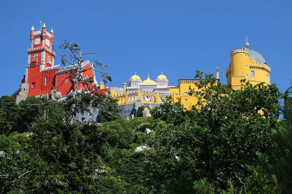 Red and yellow towers of Pena Palace above forest in Sintra