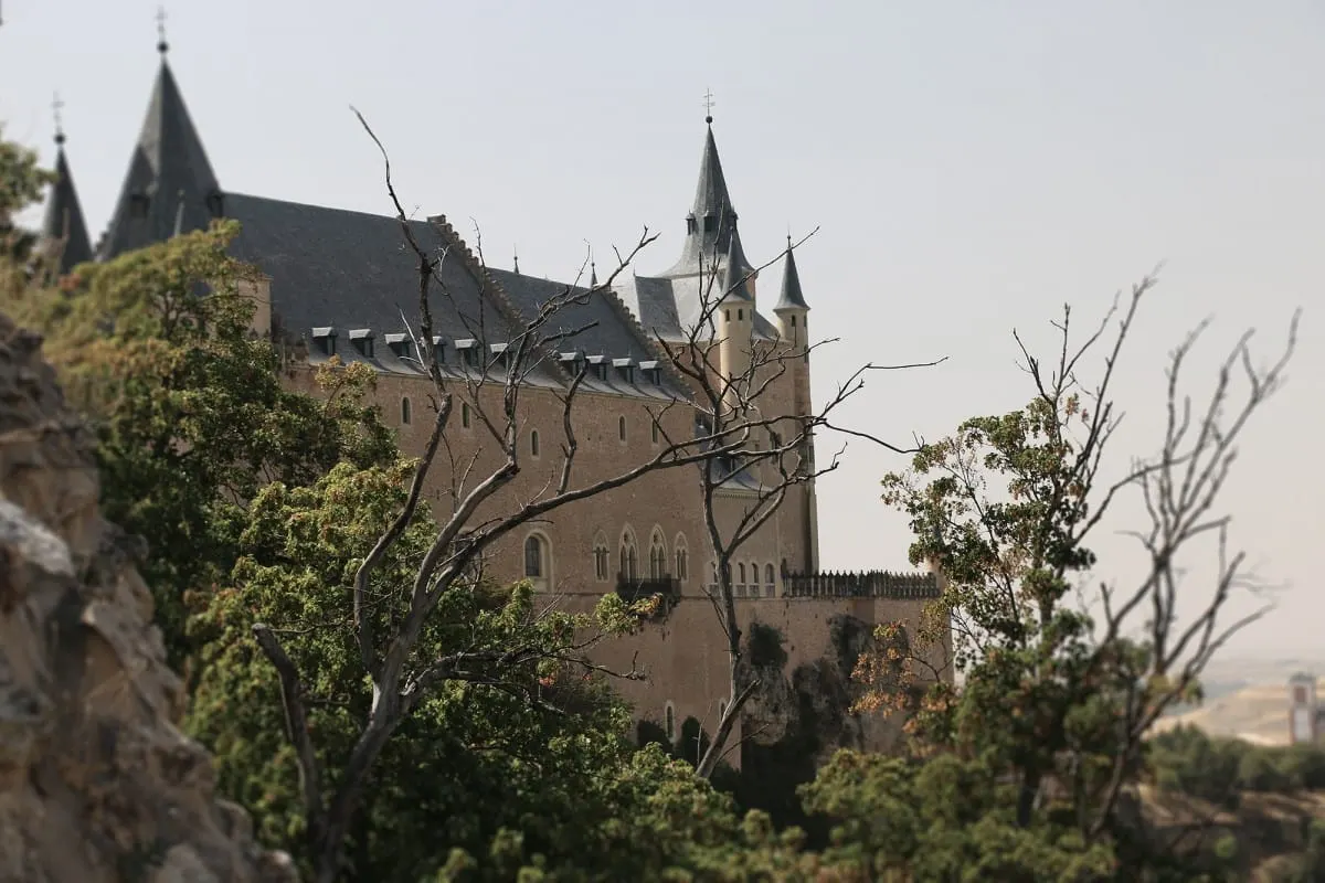 Alcazar of Segovia's slate spires seen through trees