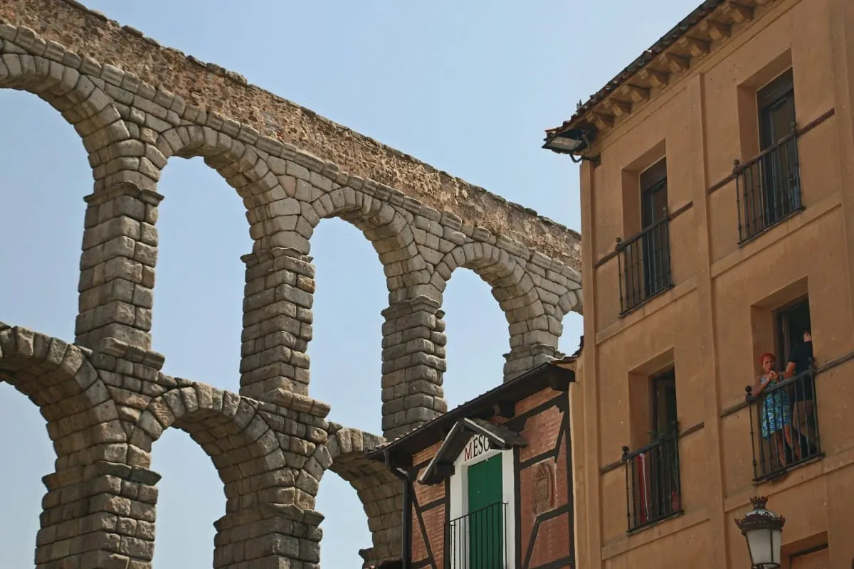 Arches of Segovia's Roman aqueduct beside a balconied building