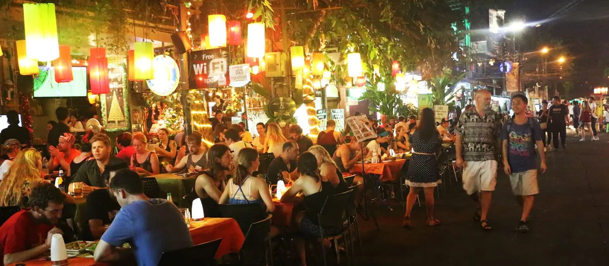 Backpackers dining under lanterns on Khao San Road at night
