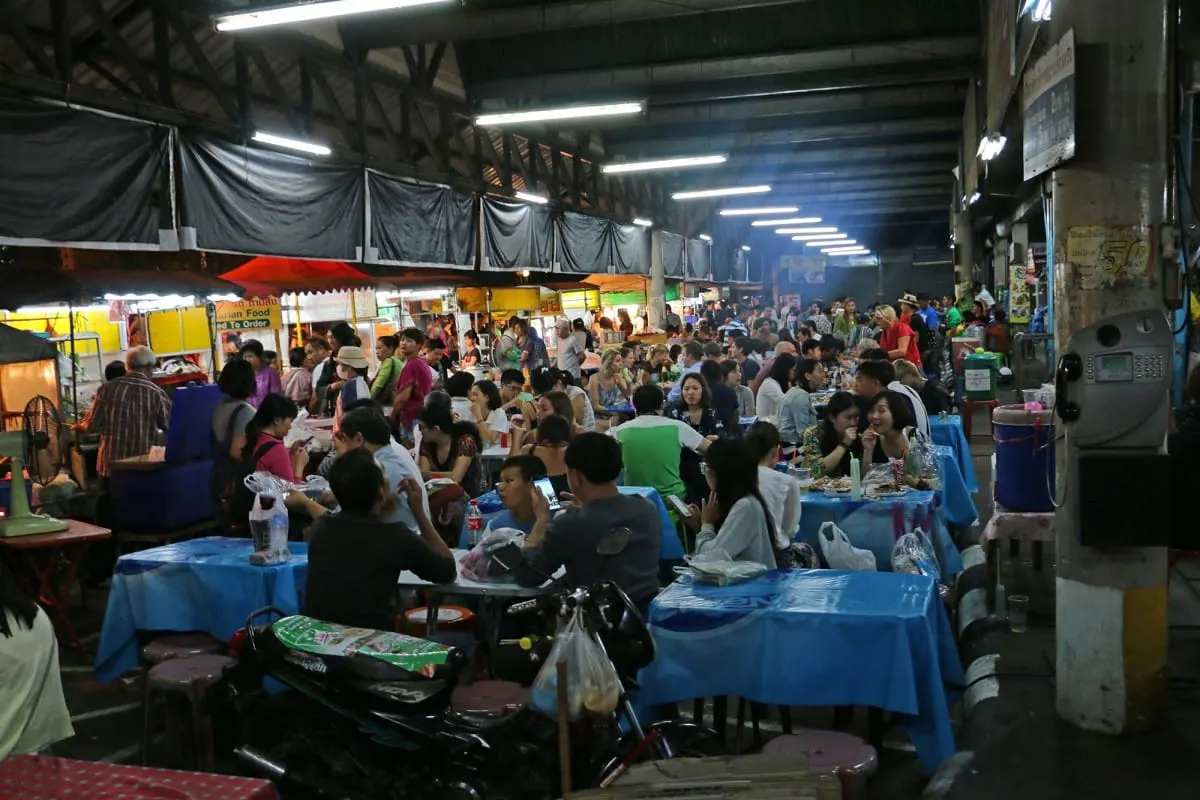 Crowded covered food market with diners at blue-covered tables, Chiang Mai
