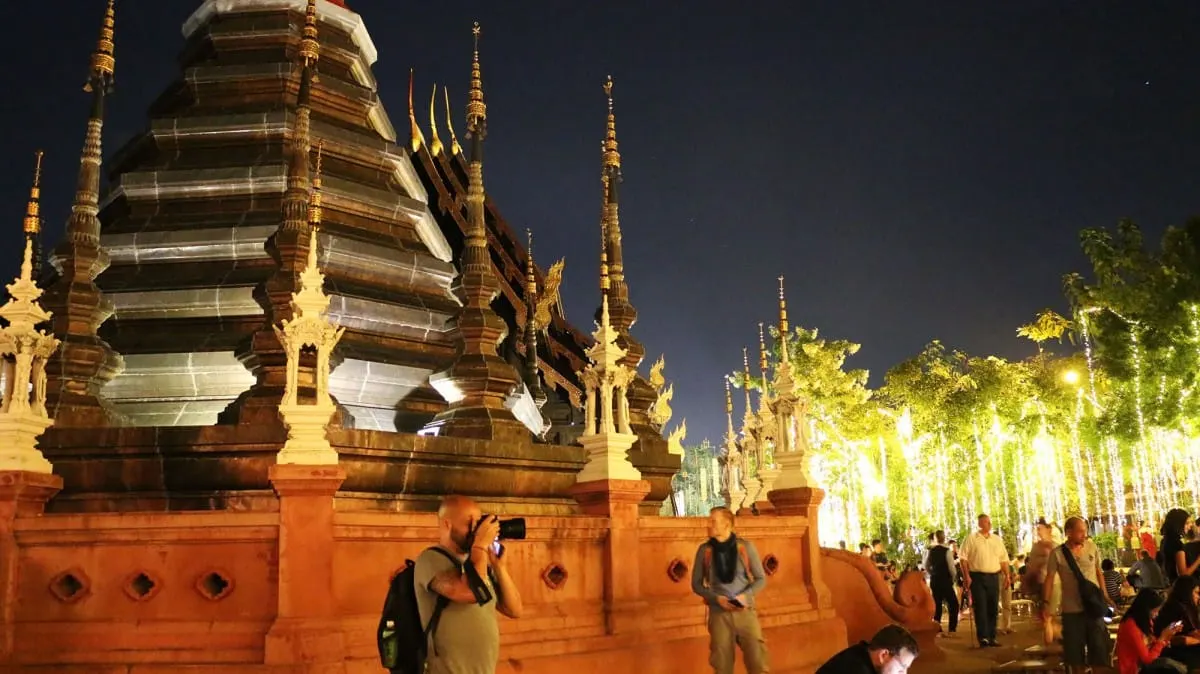 Temple spires at night beside trees strung with white lights, Chiang Mai