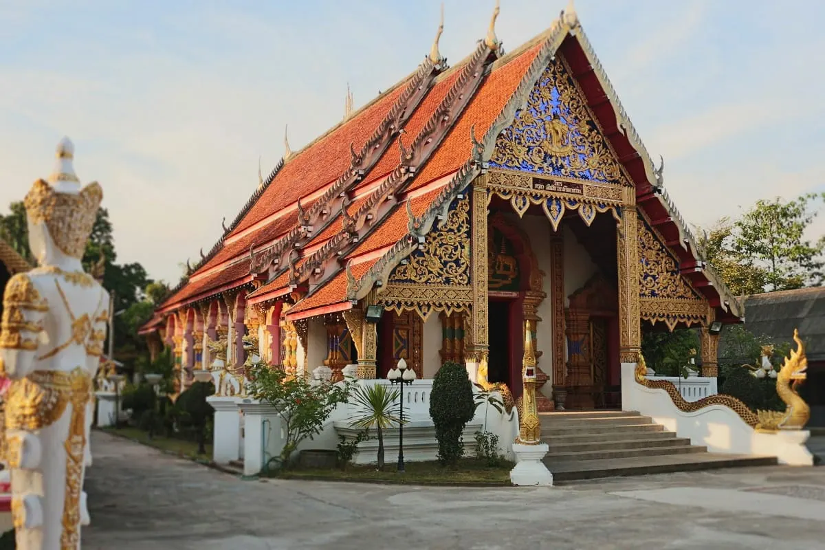 Ornate red-roofed temple hall with gilded gable and naga stair rails.