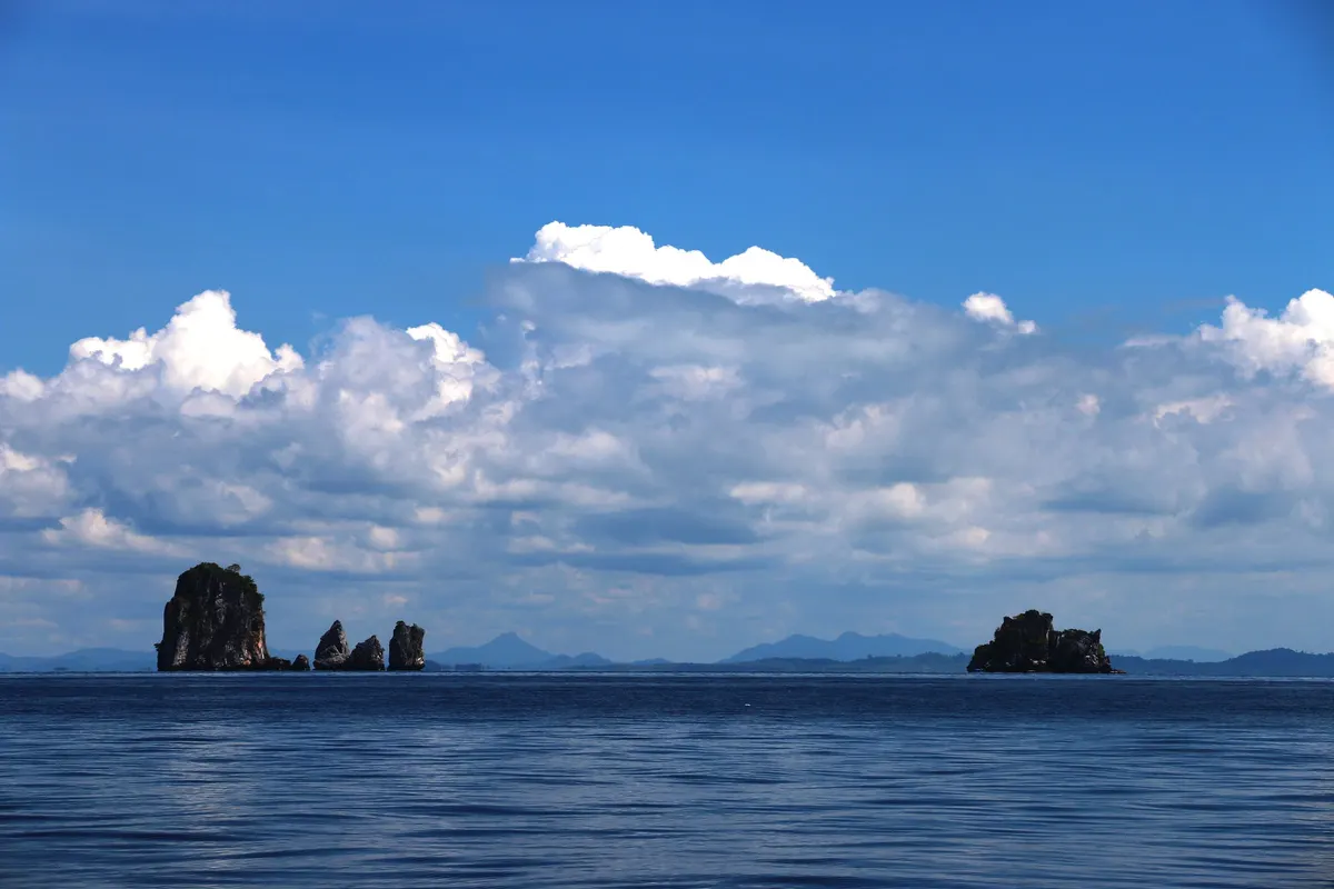 Small karst islets on the horizon under billowing clouds