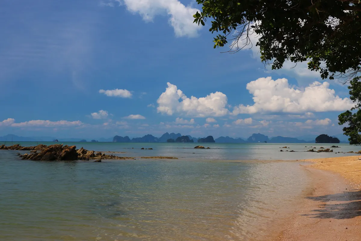 Quiet sandy cove with rocks and distant limestone islands